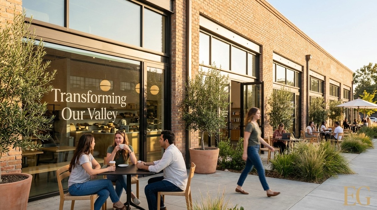 People enjoy outdoor seating at a revitalized brick commercial building, "Transforming Our Valley" on window.