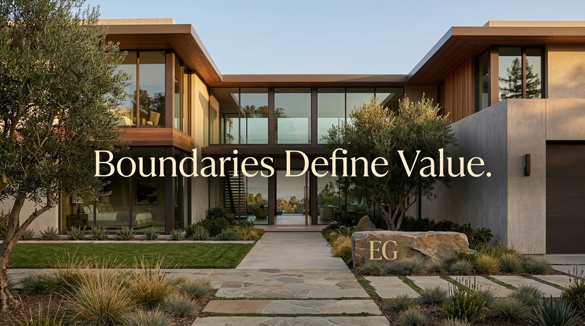 Modern luxury home with glass walls, olive trees, and a stone path. Text: "Boundaries Define Value.